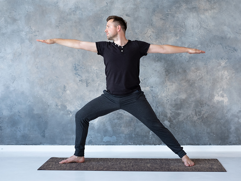 Ein Mann macht die Yoga-Übung Krieger 2.