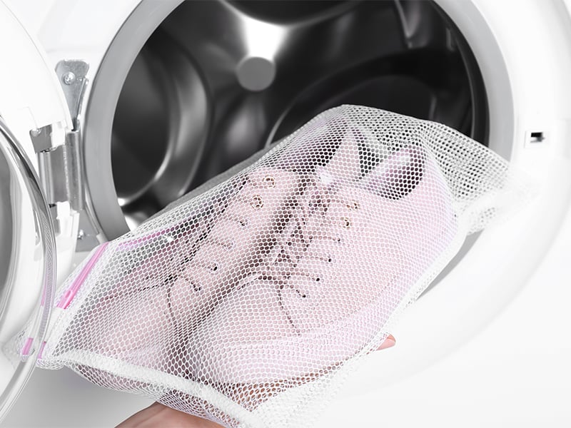 Packe die Schuhe in einen Kissenbezug (oder Waschbeutel) zum Waschen.