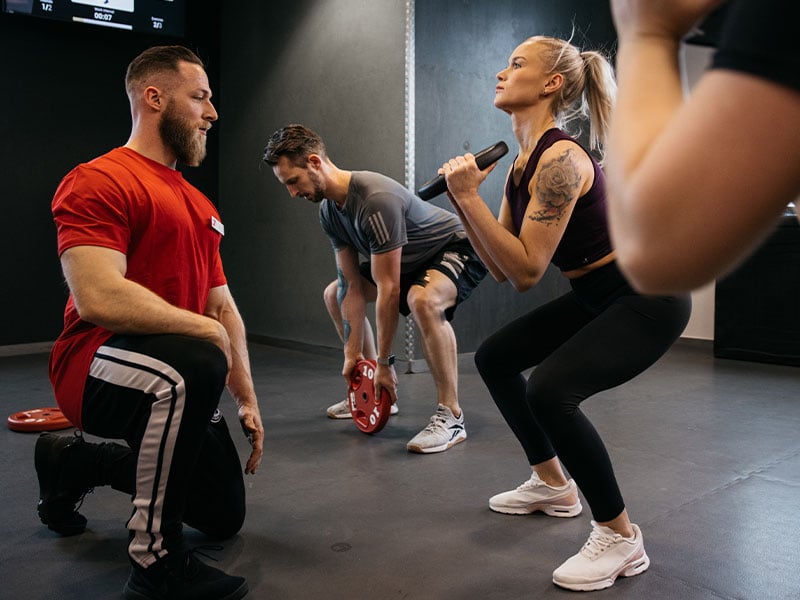 Squats mit Hantelscheibe vor der Brust („Goblet Squats“) sorgen dafür, dass du nicht nach hinten kippst.