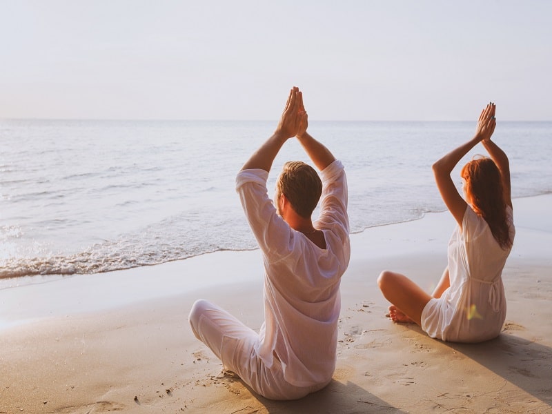 Im Urlaub ist Outdoor-Yoga am Meer total angesagt. Führe deine Sonnengrüße einfach auf weichem Sandstrand durch.